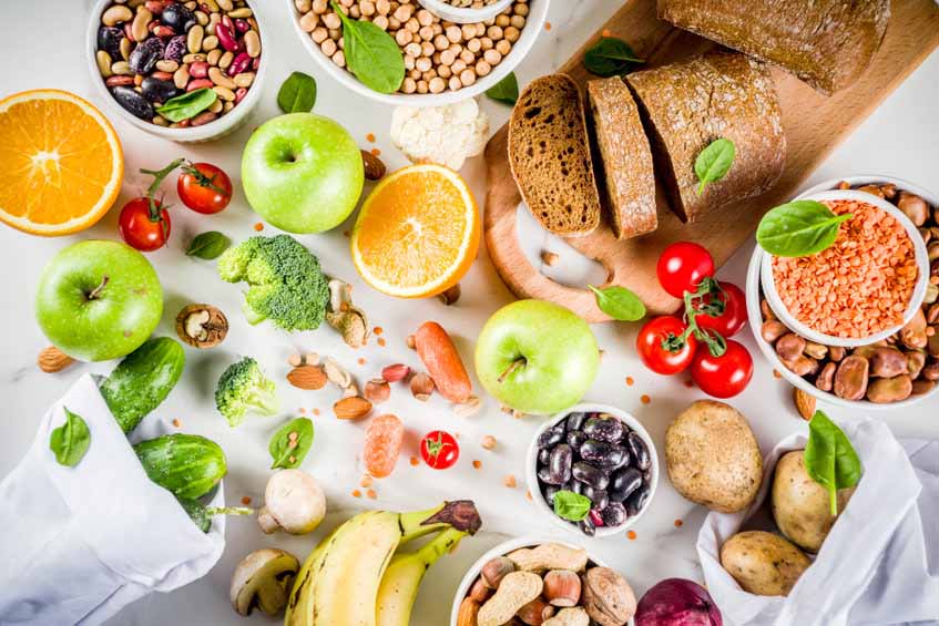 Assortment of high-fiber foods that taste good, including whole-wheat bread, fruits, nuts, and potatoes