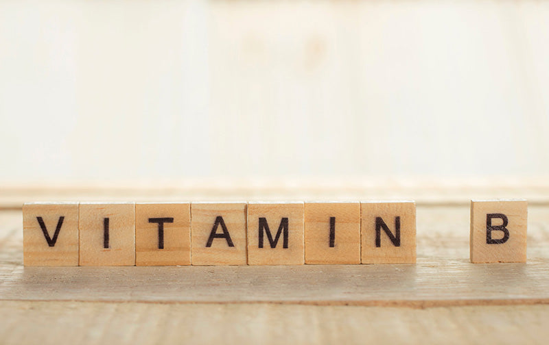  A close-up of wooden letter blocks that spell “VITAMIN B” on a wood surface