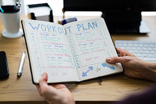 Person hält Buch mit Trainingsplan in Hand