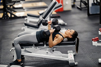 Frau trainiert im Gym mit Kurzhanteln