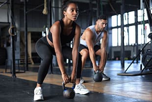 Frau und Mann beim Kettlebells Training