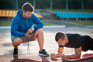 Trainer misst Zeit beim Plank