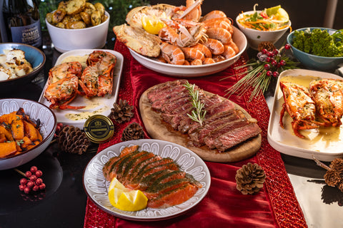 table full of lobster, steak, crab and christmas sides