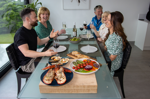 people sitting eating lobster and scallops at a dining table