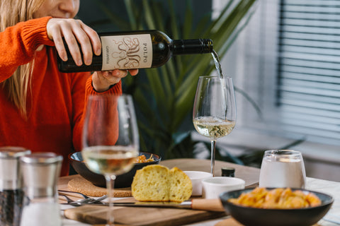 a woman pouring wine at a table with seafood linguine 