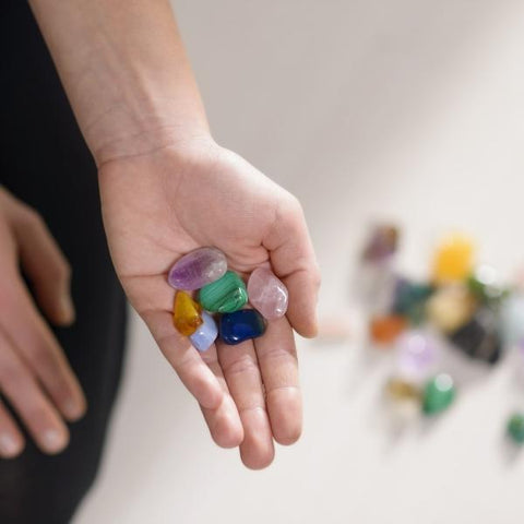 A woman holds tumbled healing crystals in her palm