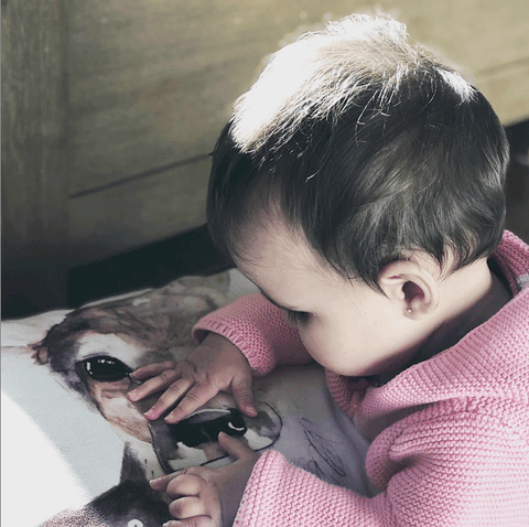 Enfant qui découvre le doux visage d'un chevreuil sur un coussin