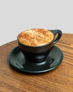 coffee drink in black mug on black saucer on wooden tabletop