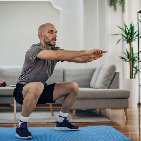 man doing air squats in living room