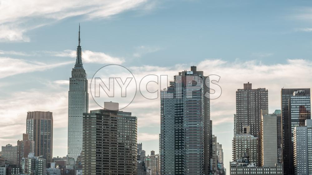 Empire State Building medium shot of Manhattan skyline early evening daytime beautiful clouds in sky New York City NYC