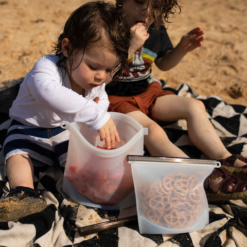 Kids at the beach eating watermelon from a reusable silicone food bag