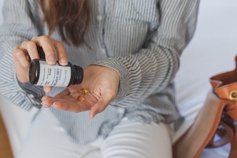 woman shaking nano CBD softgels into hand