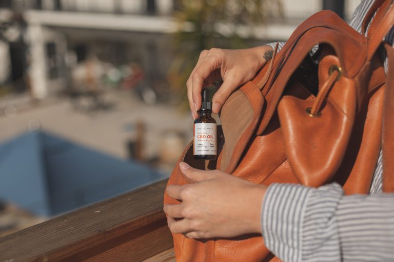 woman putting Joy Organics Orange Bliss CBD Tincture into orange bag