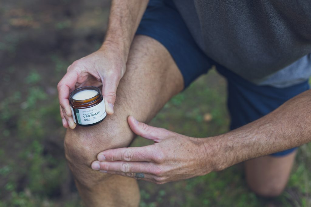 man rubbing CBD salve into knee