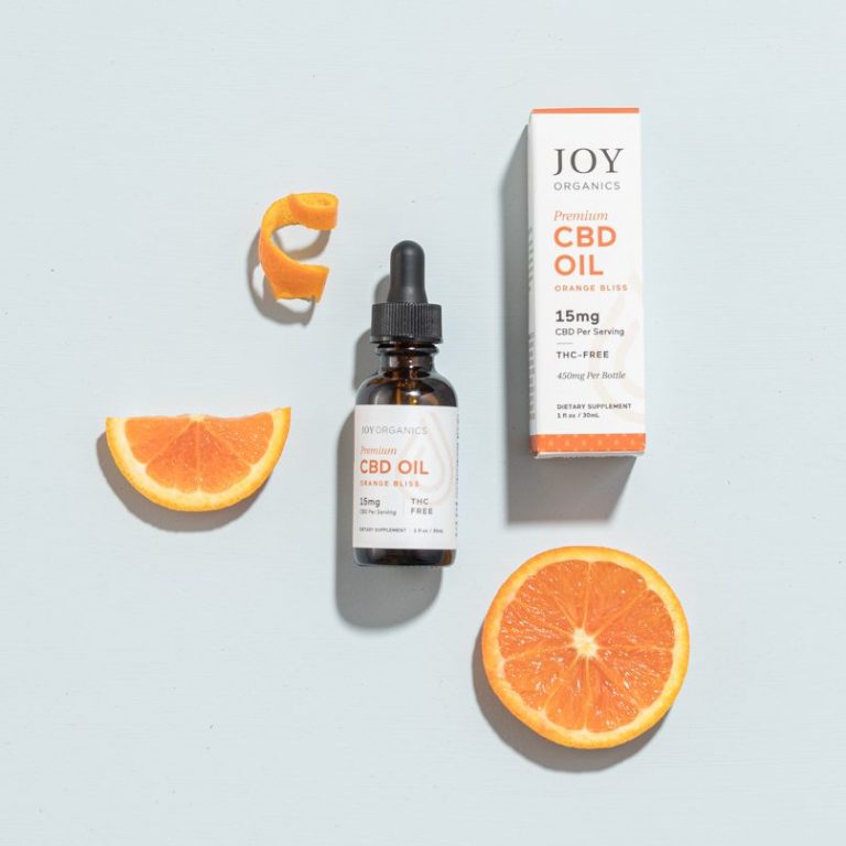 Joy Organics Orange Bliss CBD Tincture surrounded by oranges