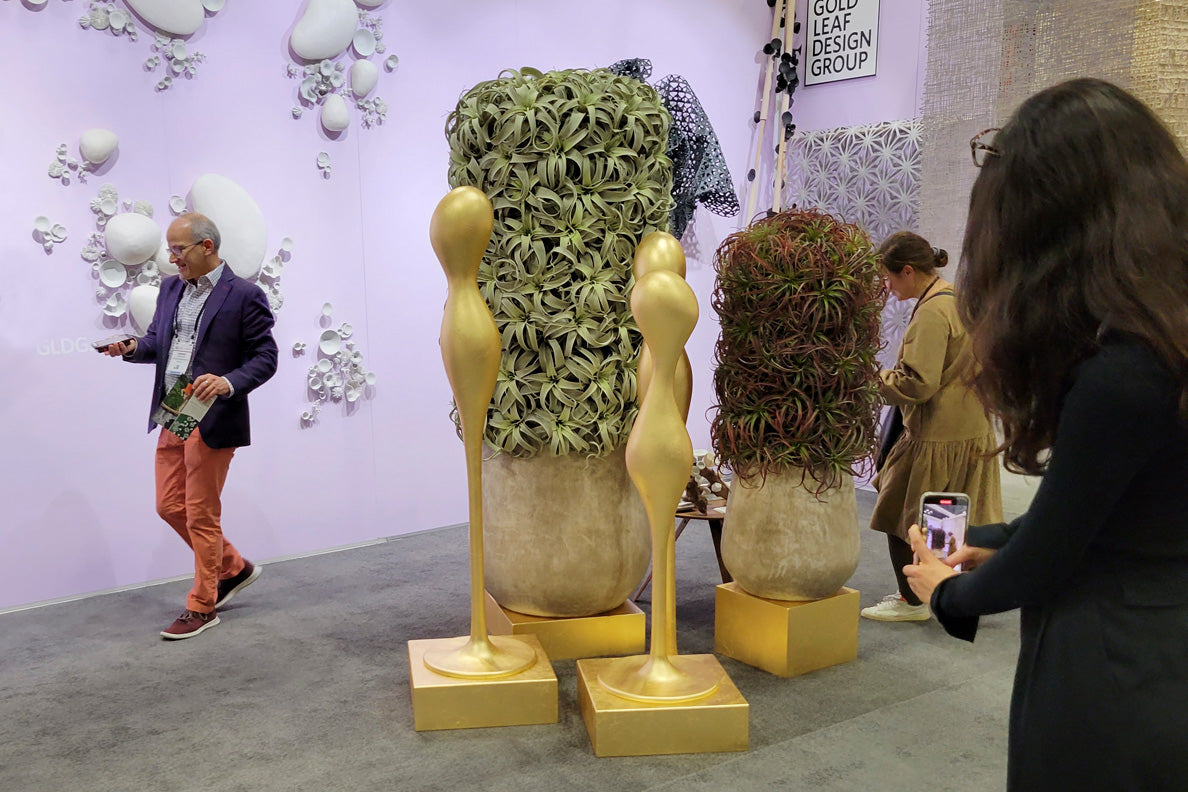 Gold Leaf Design Group's BDNY show space with a person taking photo of gold ghost sculptures in the foreground.