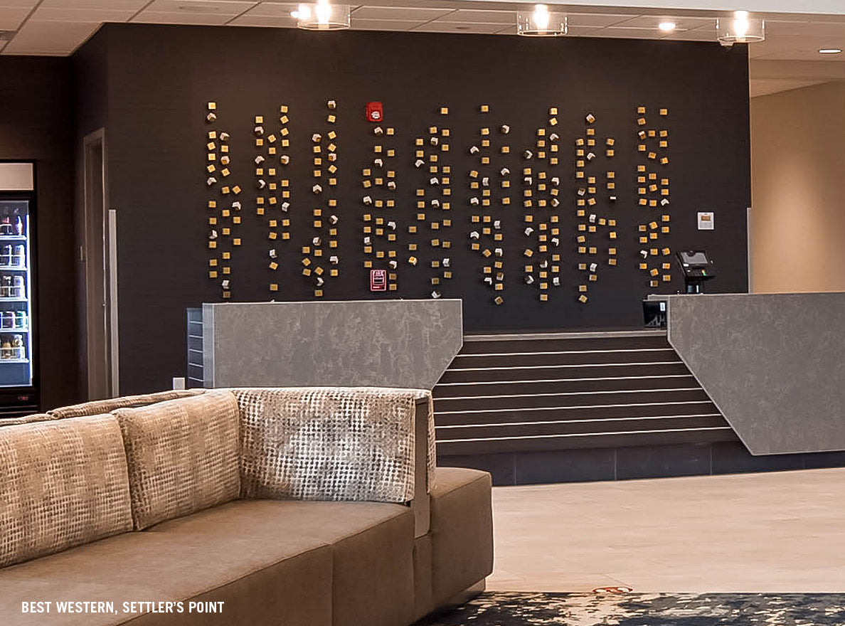 Gold and white Square and Pivot Wall Play on black wall in hotel lobby.