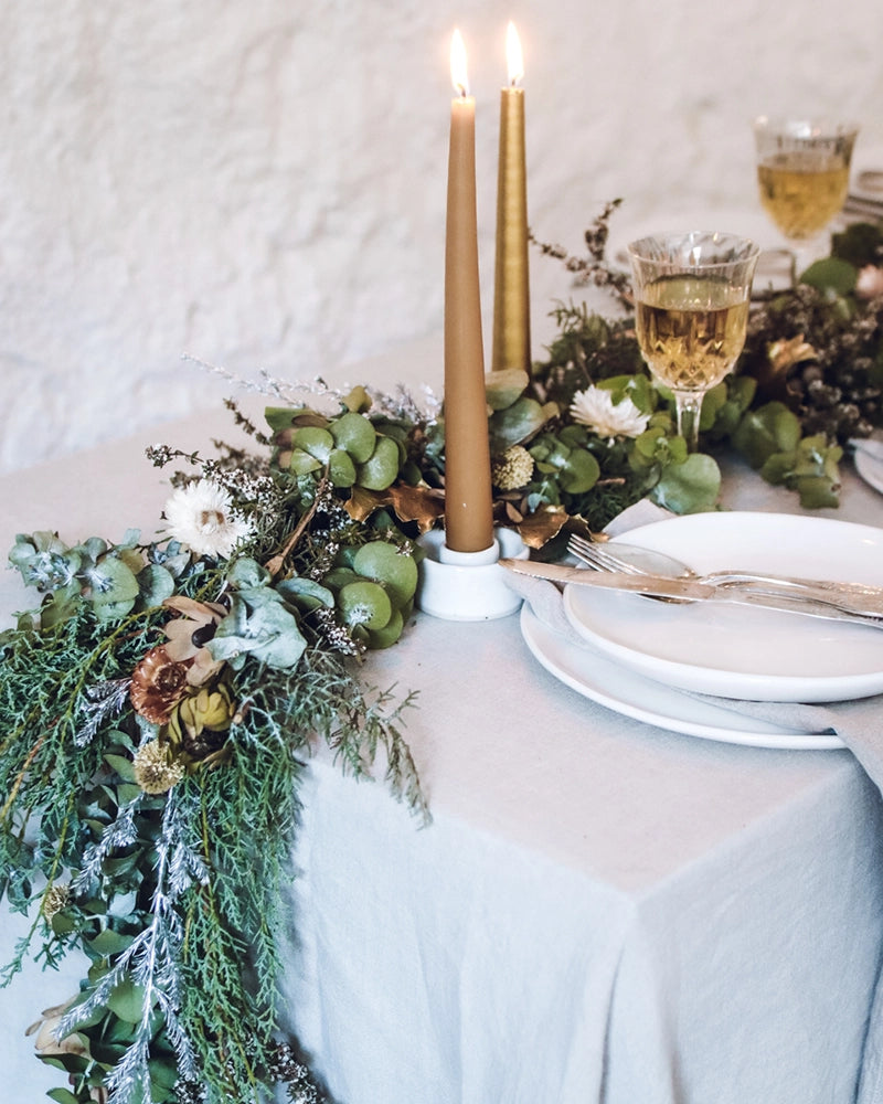A beautifully arranged native foliage garland on a white surface, showcasing eucalyptus, flowers, and pine branches
