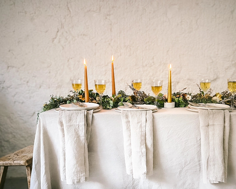 Elegant Christmas table setting featuring a native foliage garland centrepiece, almond butter tapered candles, and crystal wine glasses.