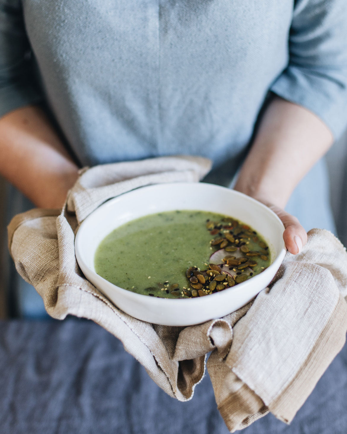 Winter pea and mint soup, sprinkled with pepitas in a stoneware handmade bowl