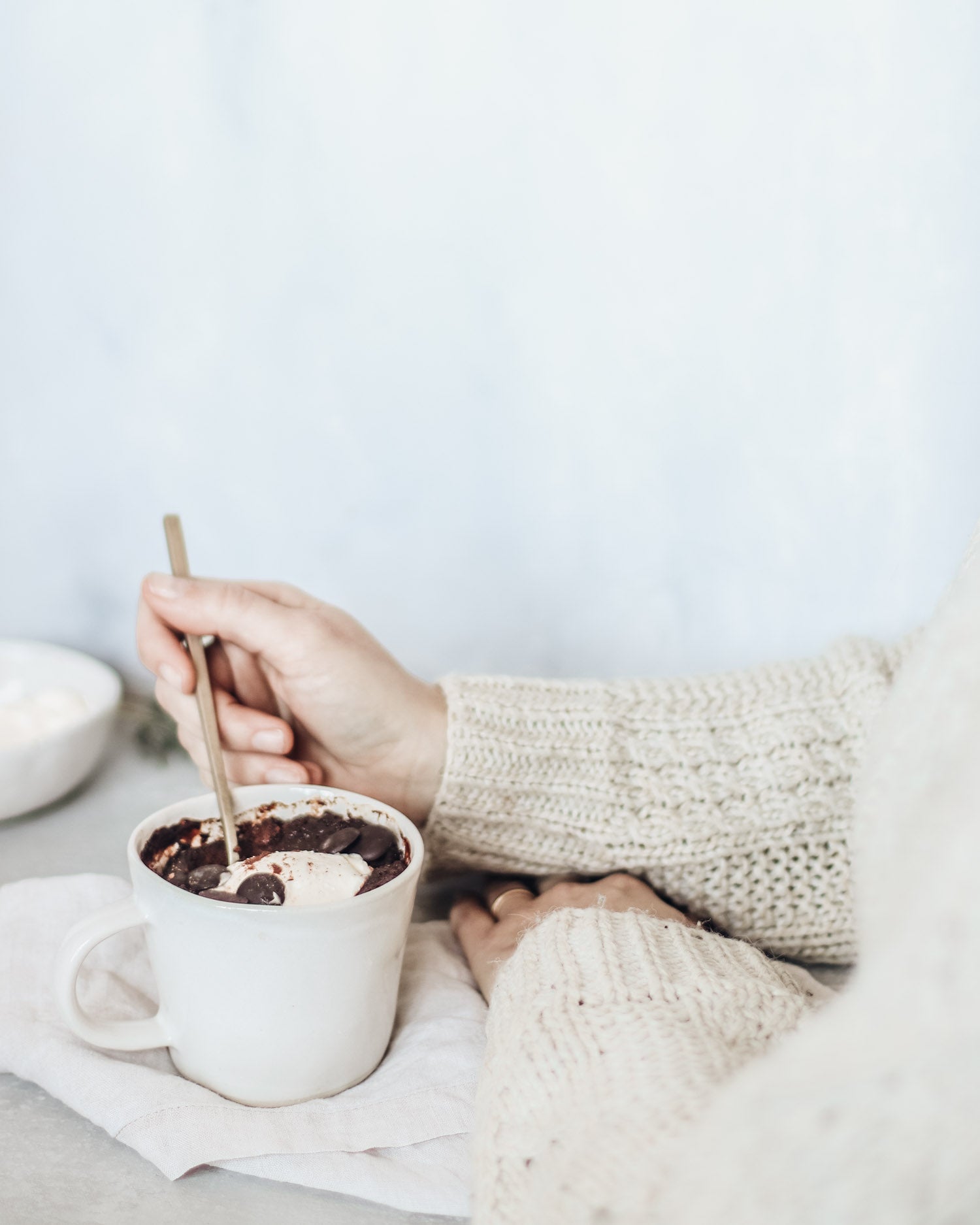 Baked chocolate pudding in a mug being enjoyed topped with cream