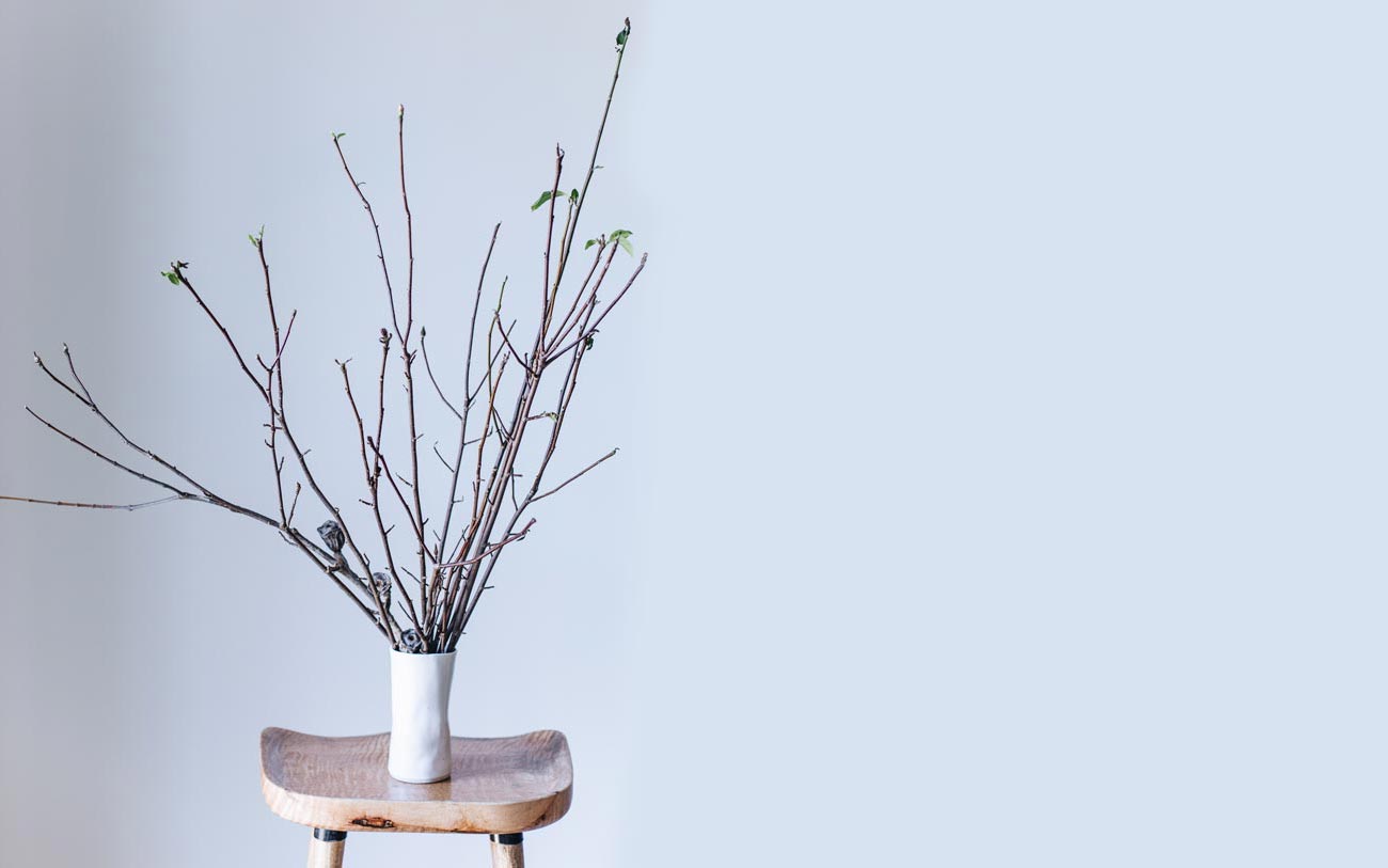 Winterwares vase perched on stool holding branches 