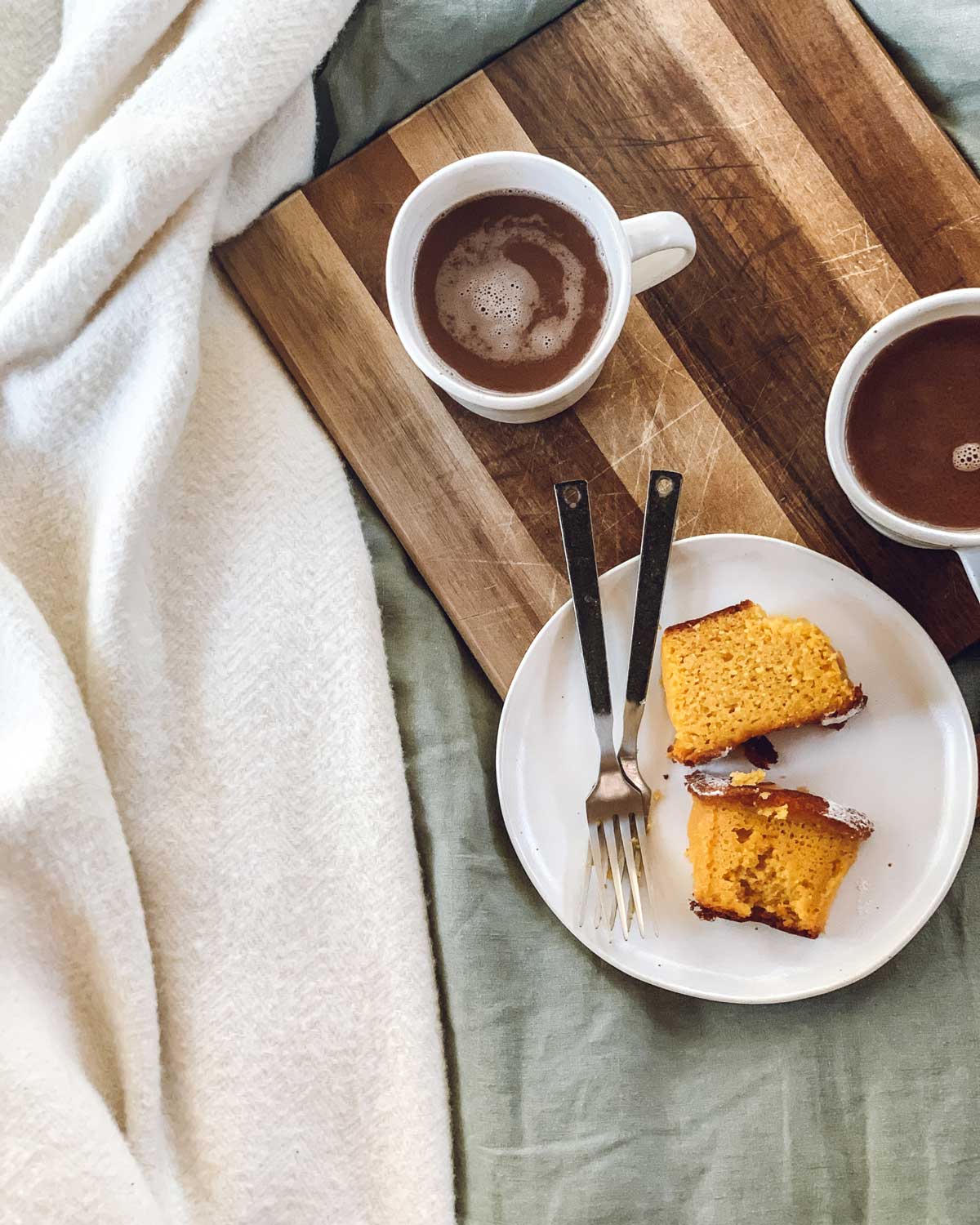 Orange cake and two cups of coffee on a on a tray in bed 