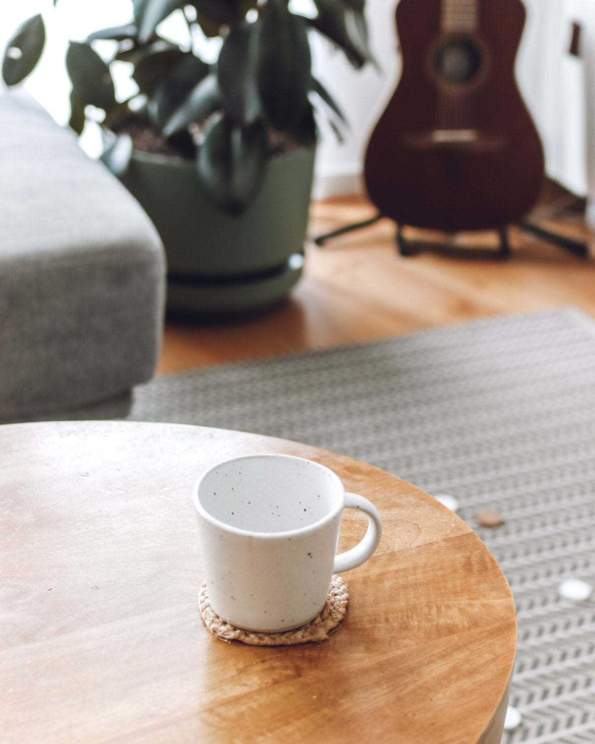 Coffee mug on the table with plants and rug in the background