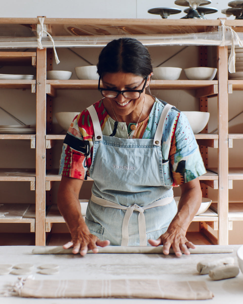 Woman rolling out clay coils in a pottery studio