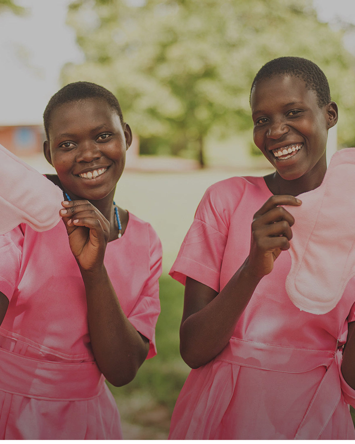 Two school aged girls holding up reusable sanitary pads 