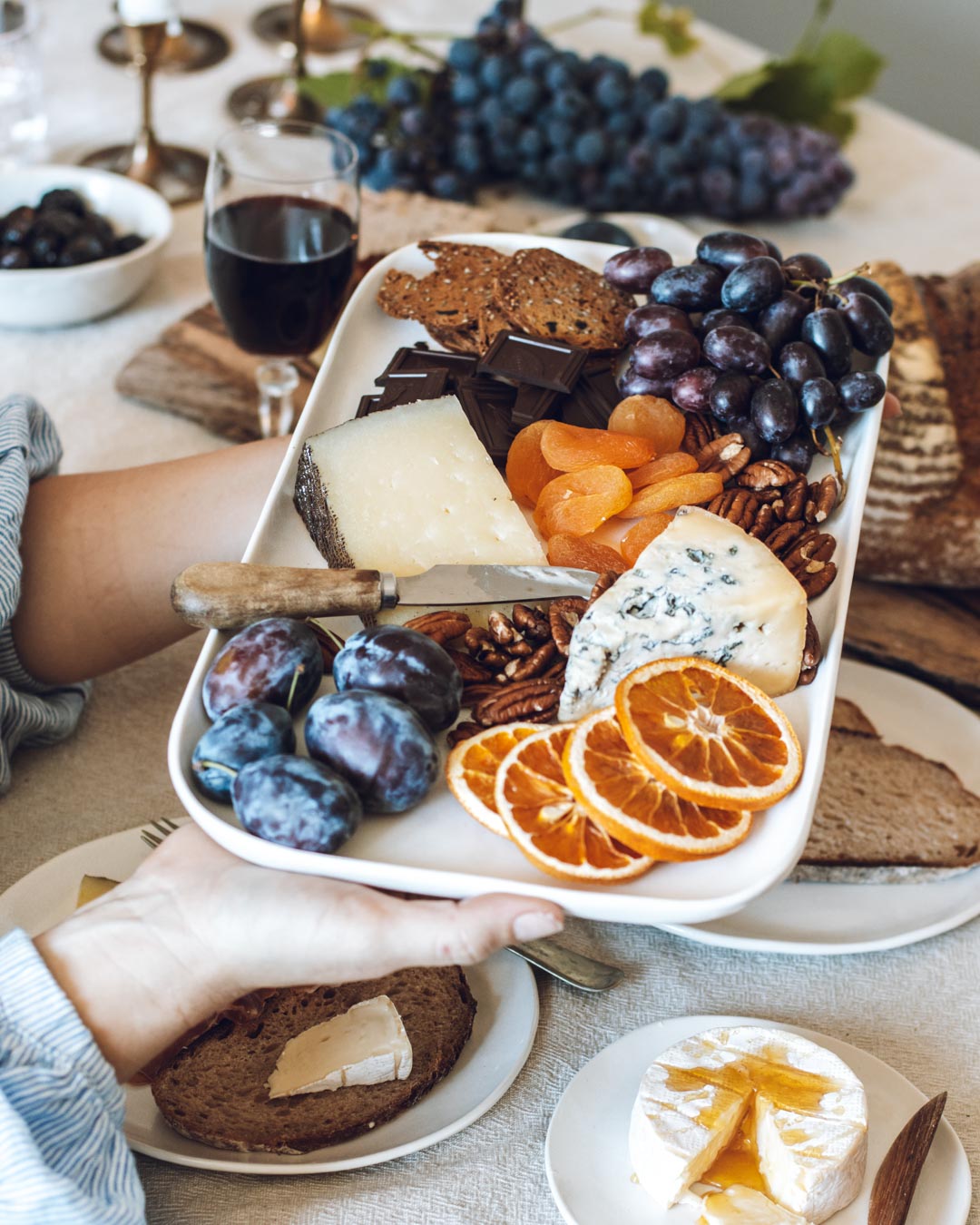 Holding a platter of grapes, crackers and cheese. 