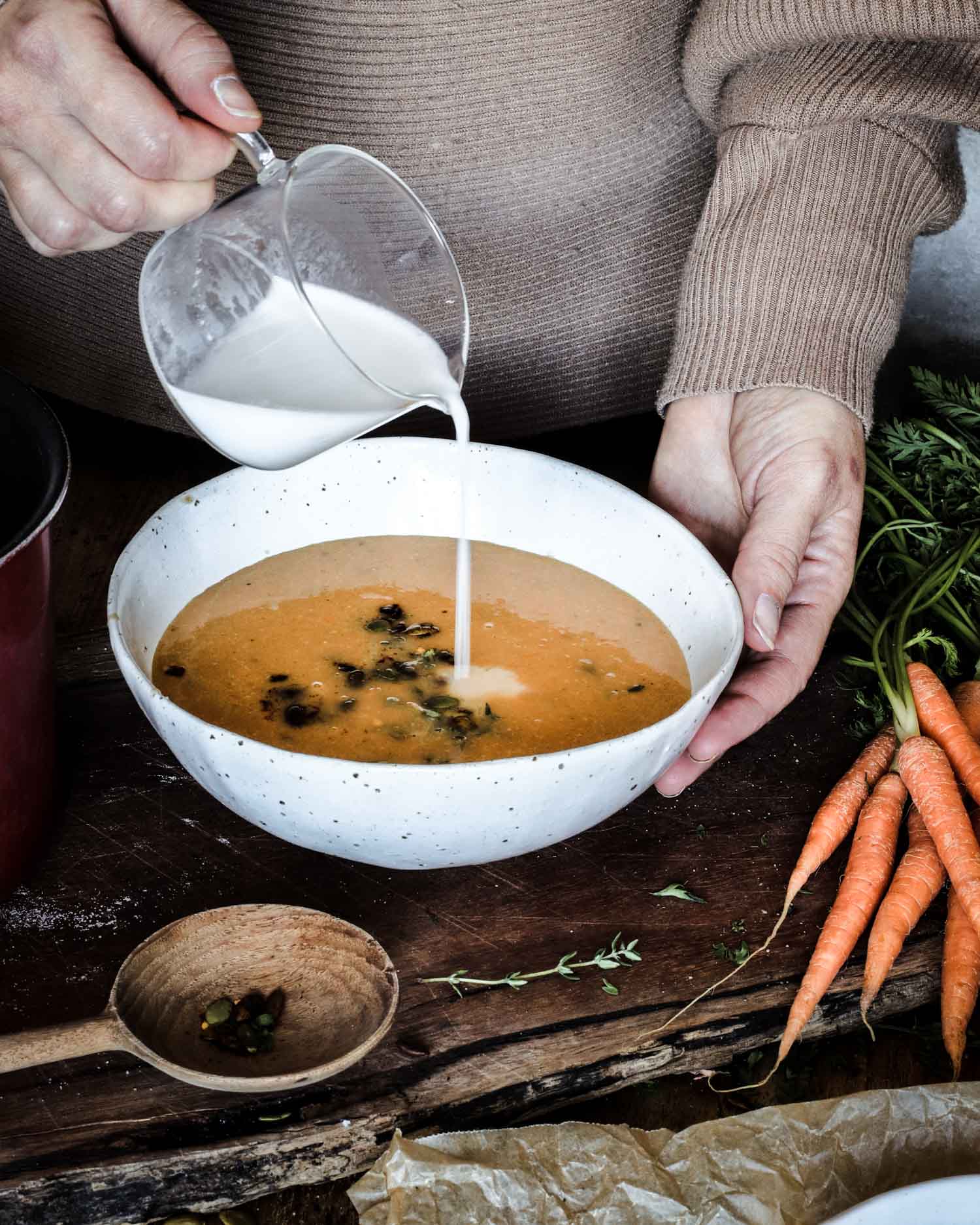 Pouring coconut cream into carrot soup