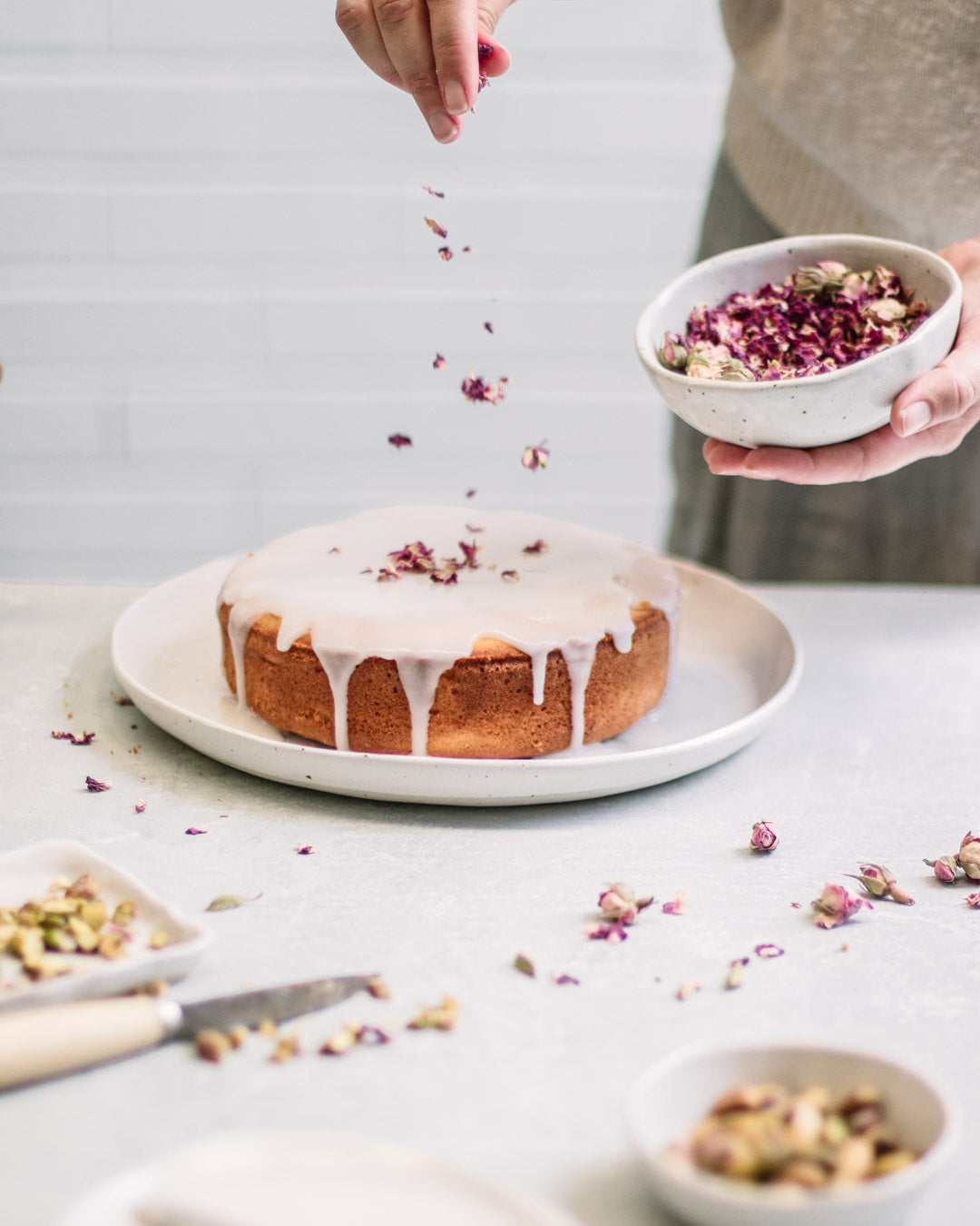 Persian Love Cake decorated with lemon icing, rose petals and pistachios