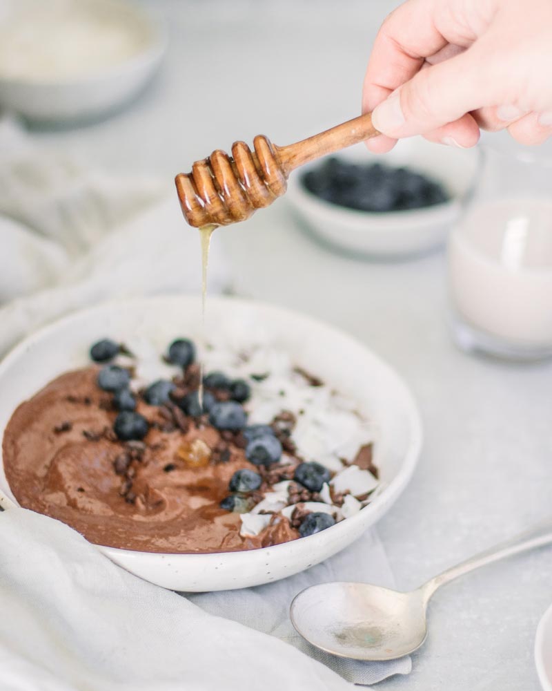 Pouring honey into a chocolate smoothie bowl