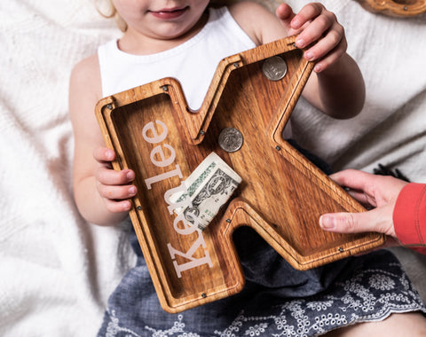 child holding first piggy bank - first birthday gift idea