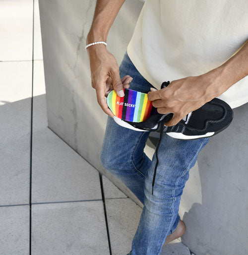 person placing rainbow sock insert into black shoe