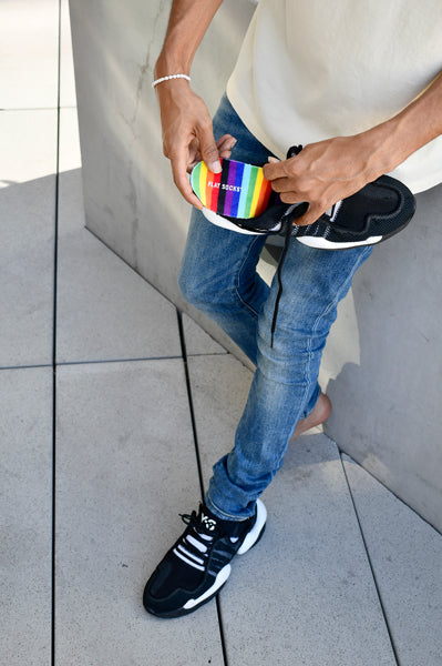 Man putting rainbow FLAT SOCKS shoe insert into black shoe