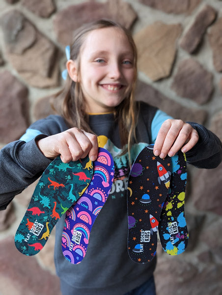 girl holding four FLAT SOCKS Kids sock inserts