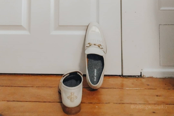 White loafers sitting by door with grey FLAT SOCKS inside