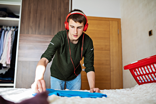 College student folding clothes on bed