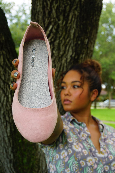 woman holding pink ballet flat with light grey sock insert inside