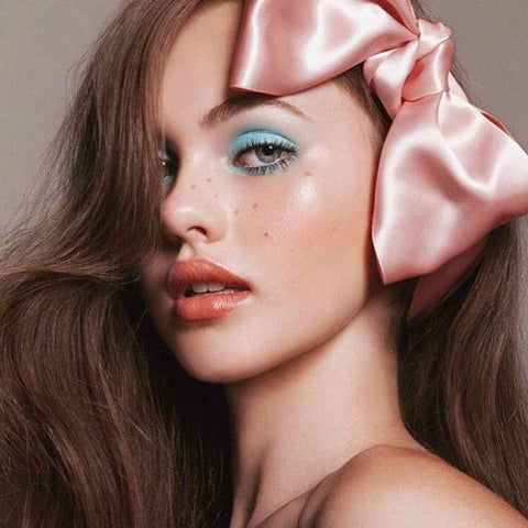 Model with pink satin bow and freckles