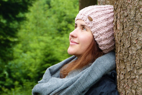 woman standing with her back against a tree smiling and taking in the sights as she inhales deeply