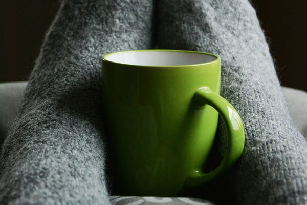 woman sitting with a mug of green tea between her cozy socked feet