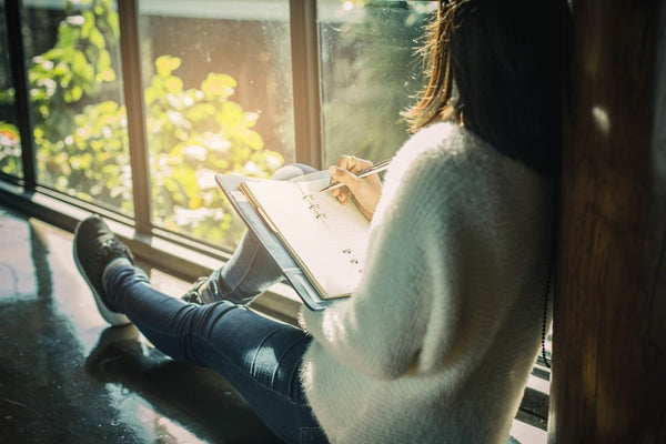 woman sitting in windowsill journaling