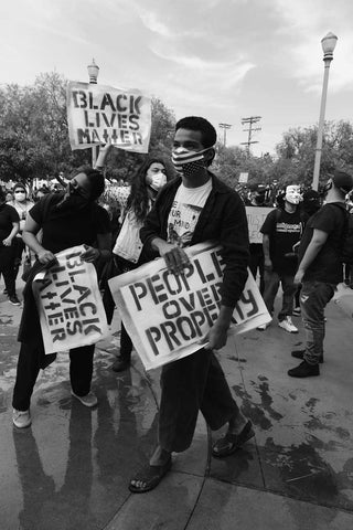 black lives matter rally with protestors in masks and sign saying "People Not Property"