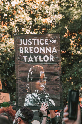 white hand holding a sign saying justice for Breonna Taylor