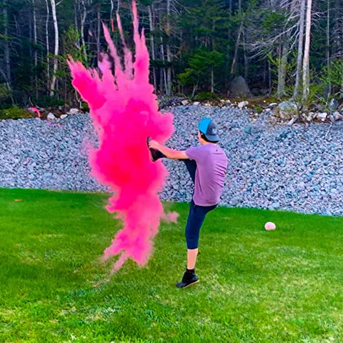 A man kicked a ball that has pink powder in it.