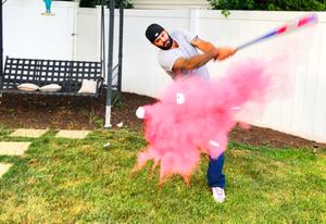 A guy popped a ball that has pink powder using a baseball bat