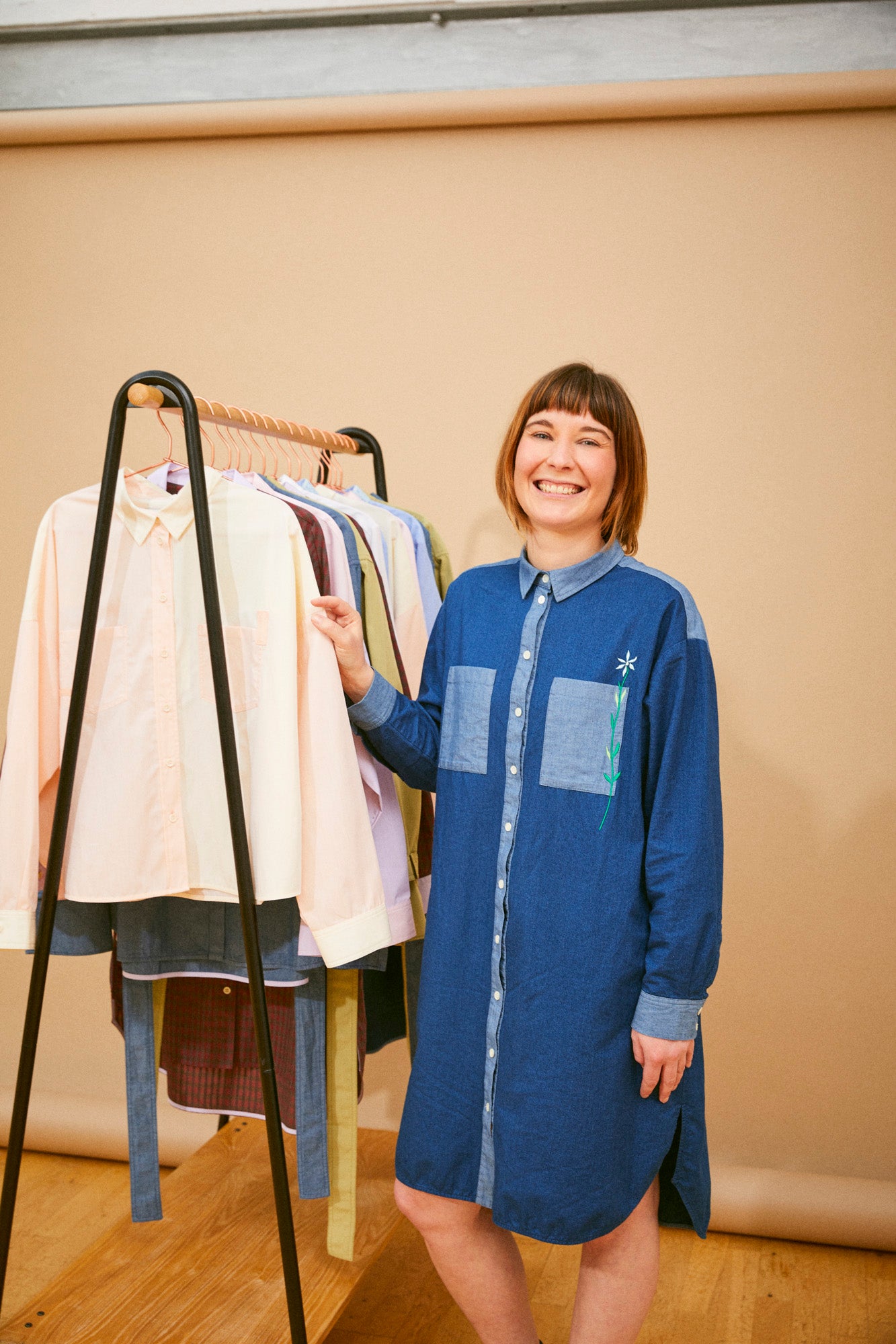 Saywood founder, Harriet, standing next to a rail of Saywood timeless shirts